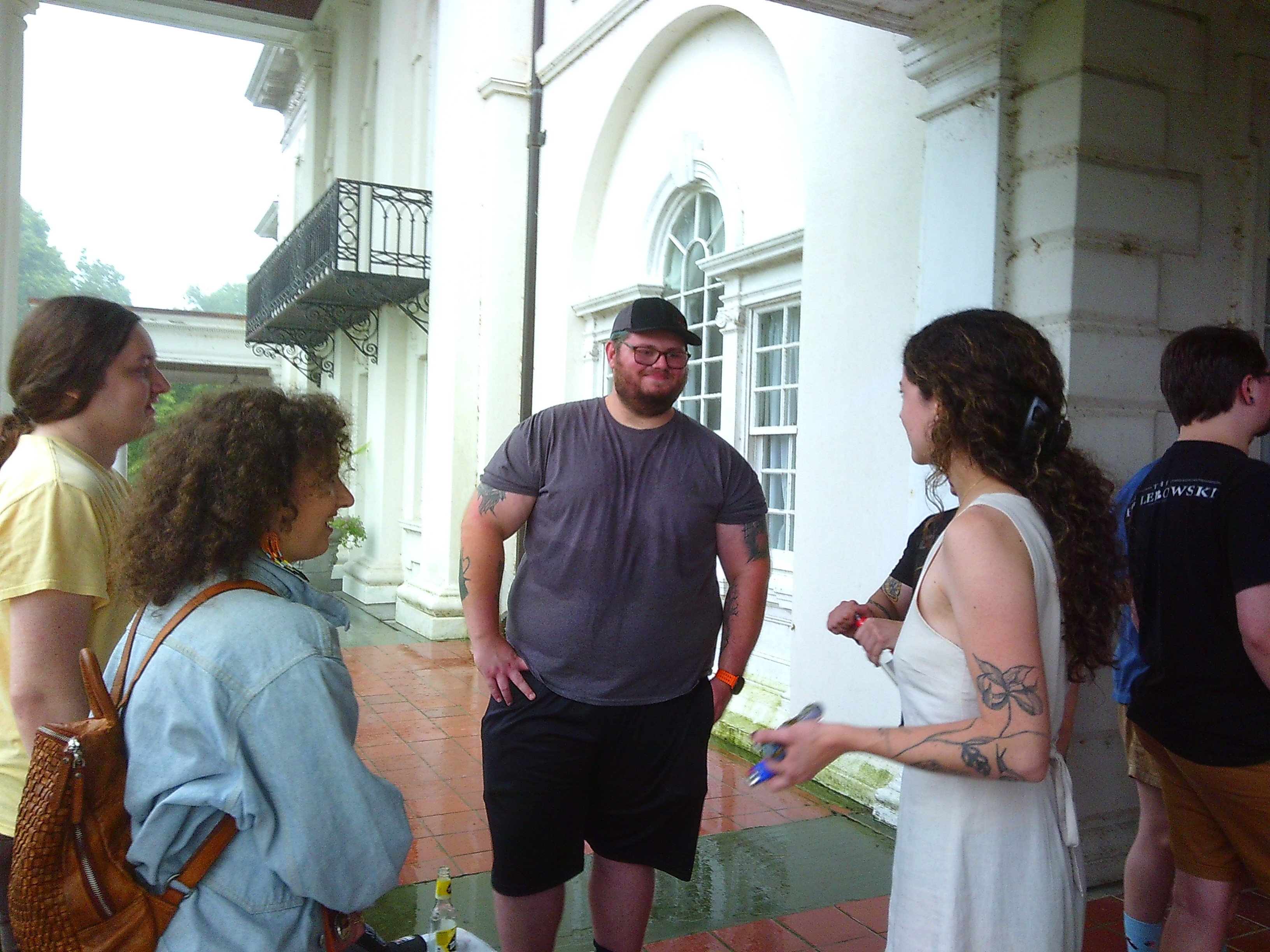 photo of a few people standing in somewhat of a circle, with one man smiling at a woman while they talk