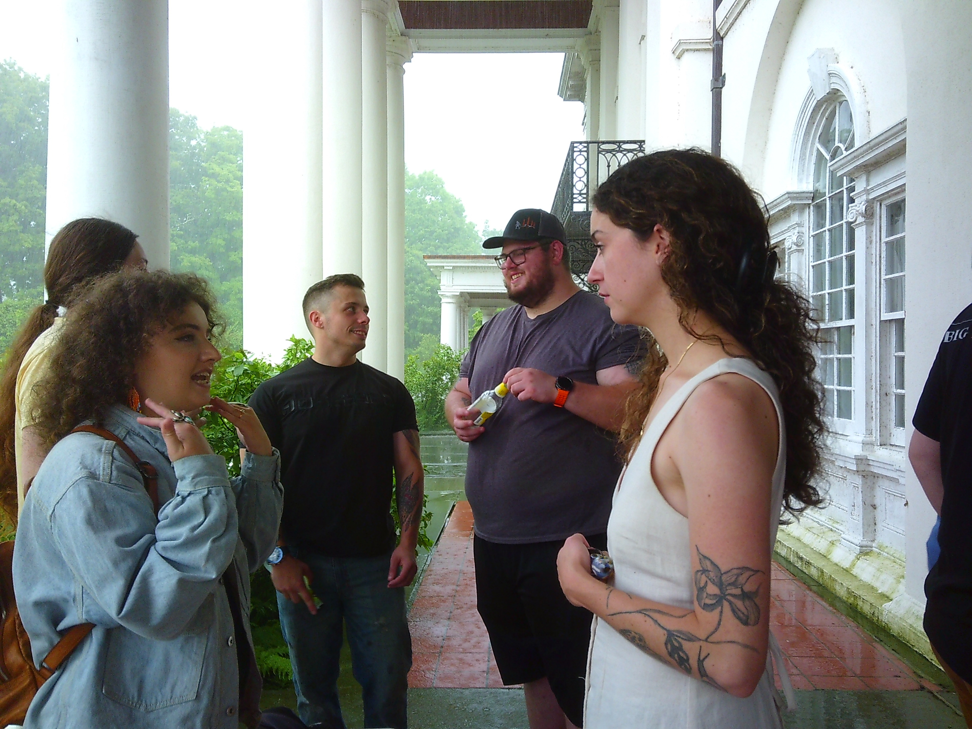 Photo of a group of people in a rough circle, with two women in the foreground talking to each other and two men in the background talking with each other.