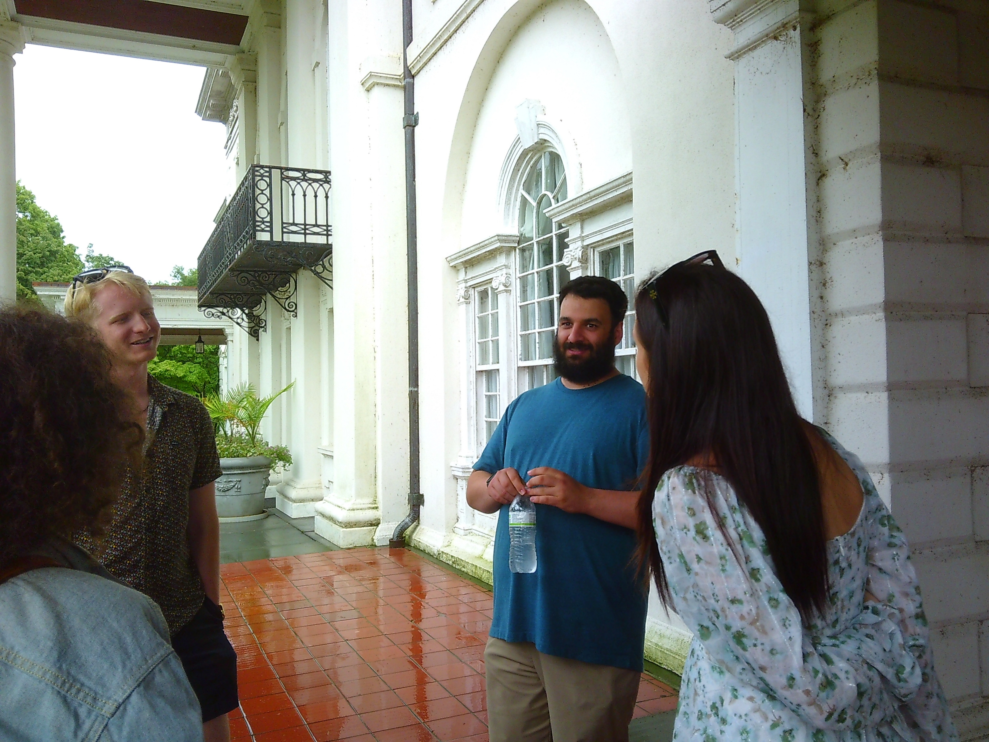 Photo of 4 people in a rough circle. One man in a bright blue shirt appears to be in the middle of saying something