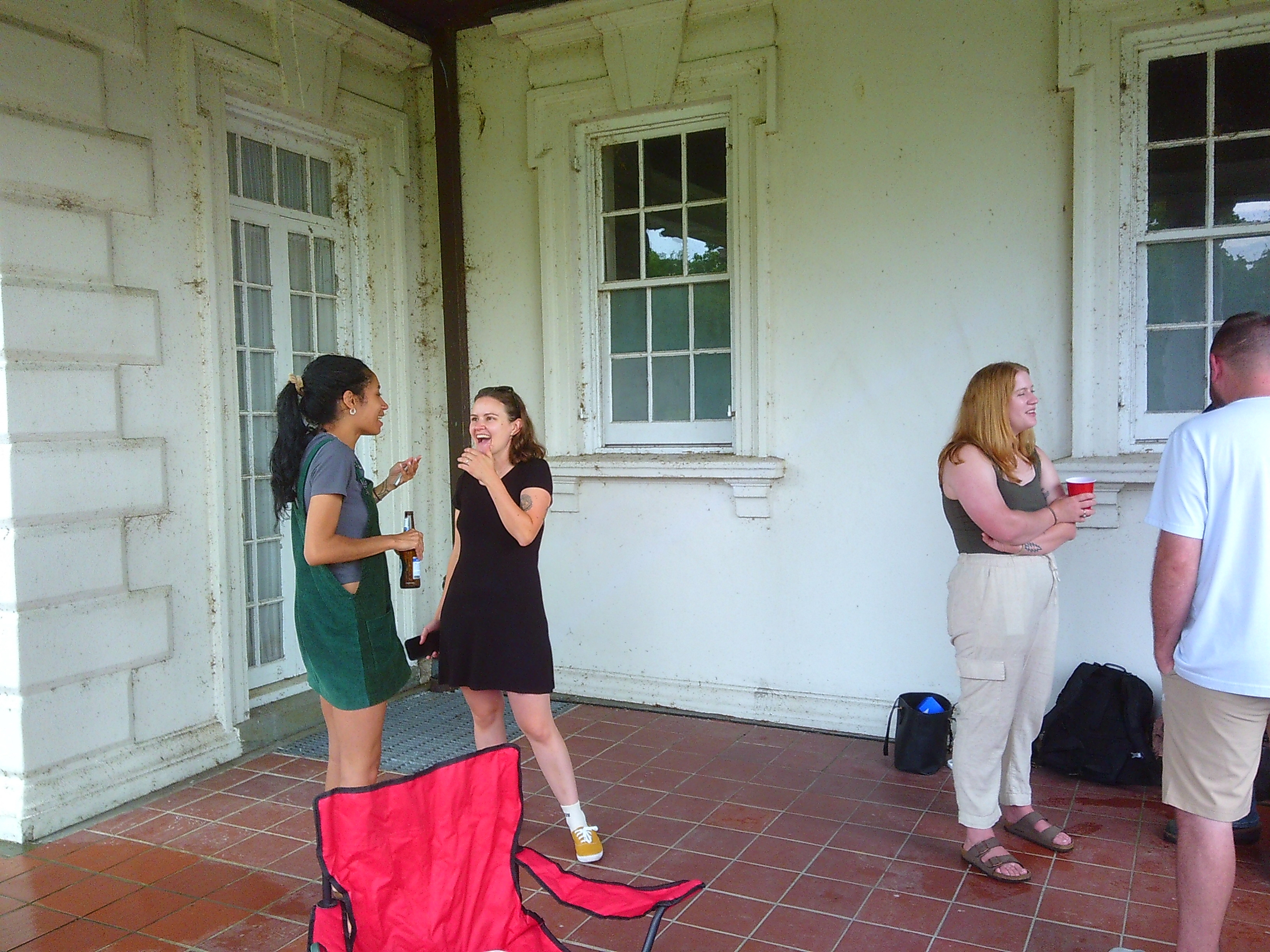 Photo of 4 people, two on the left side of the frame, two on the right. The two women on the left are both smiling and seem to be mid laugh. The man and woman on the right seem to be mid conversation