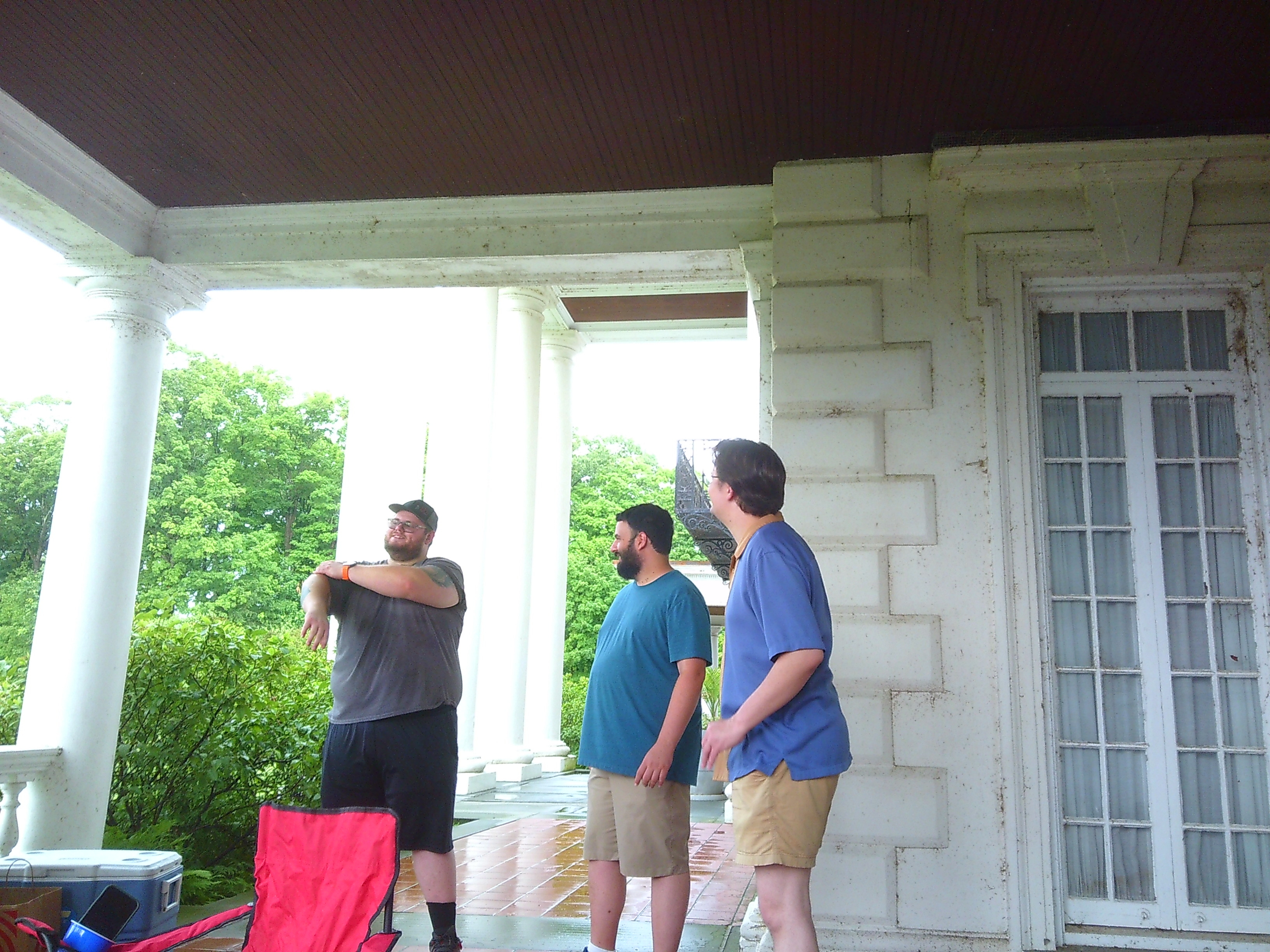 Photo of three men, one seems to be mid stretch while the other two look at him