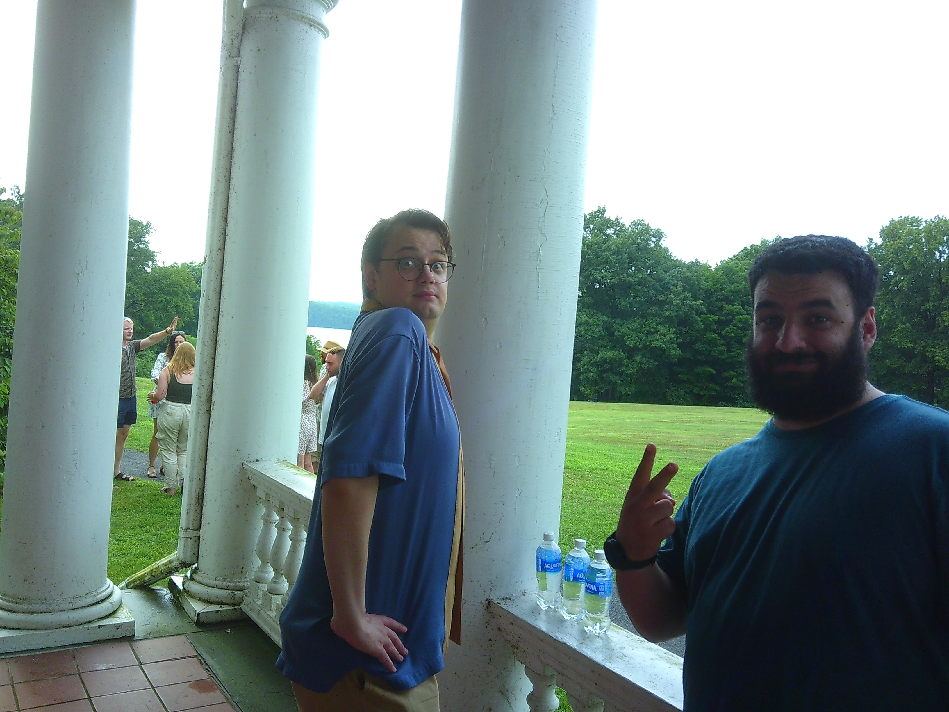 Photo of two men where one is sideways making a silly face towards the camera while the other is holding the peace sign