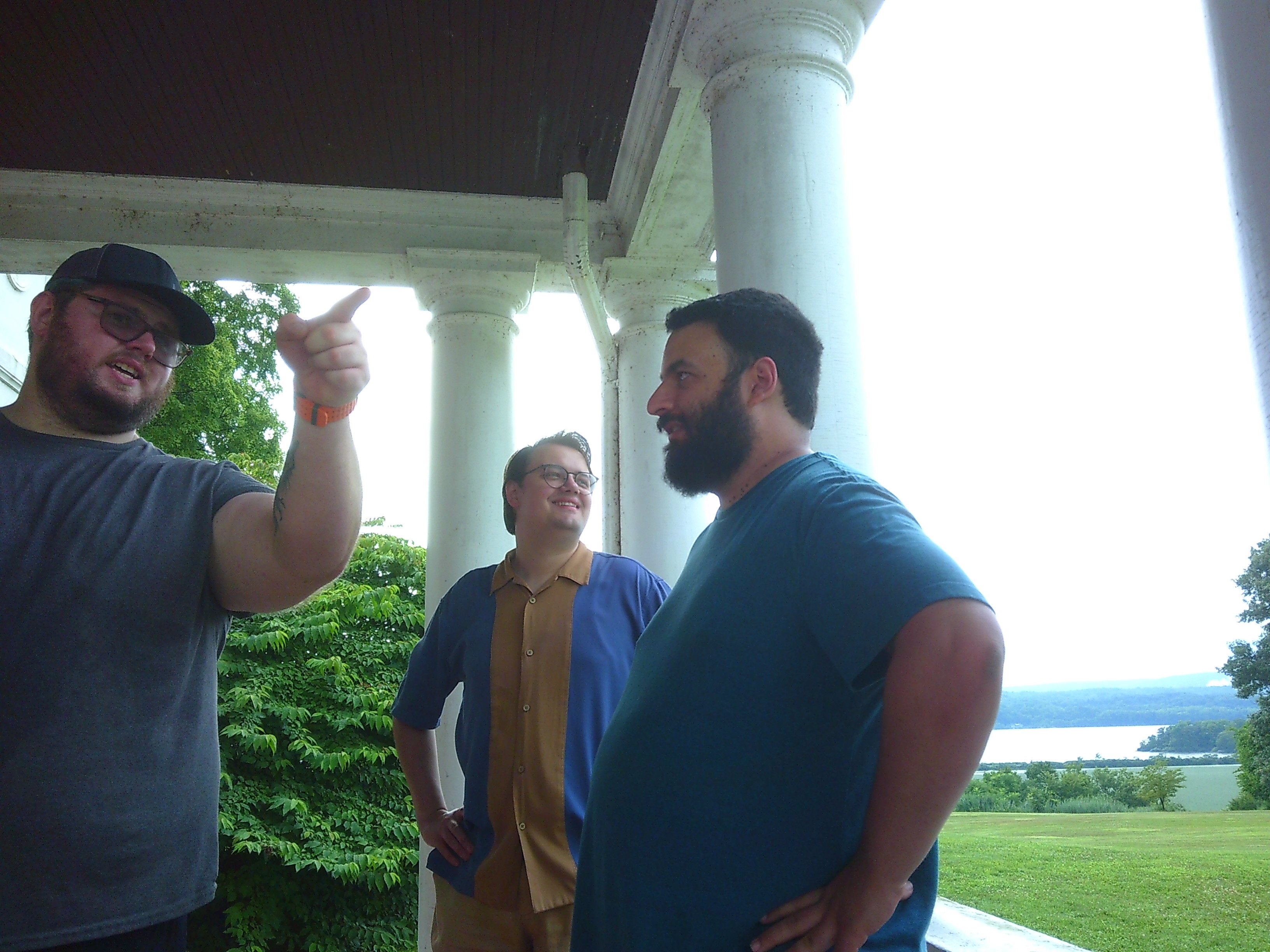 Photo of three men talking. One is pointing off camera, one is looking in the same direction as the point, and one is looking at the man pointing