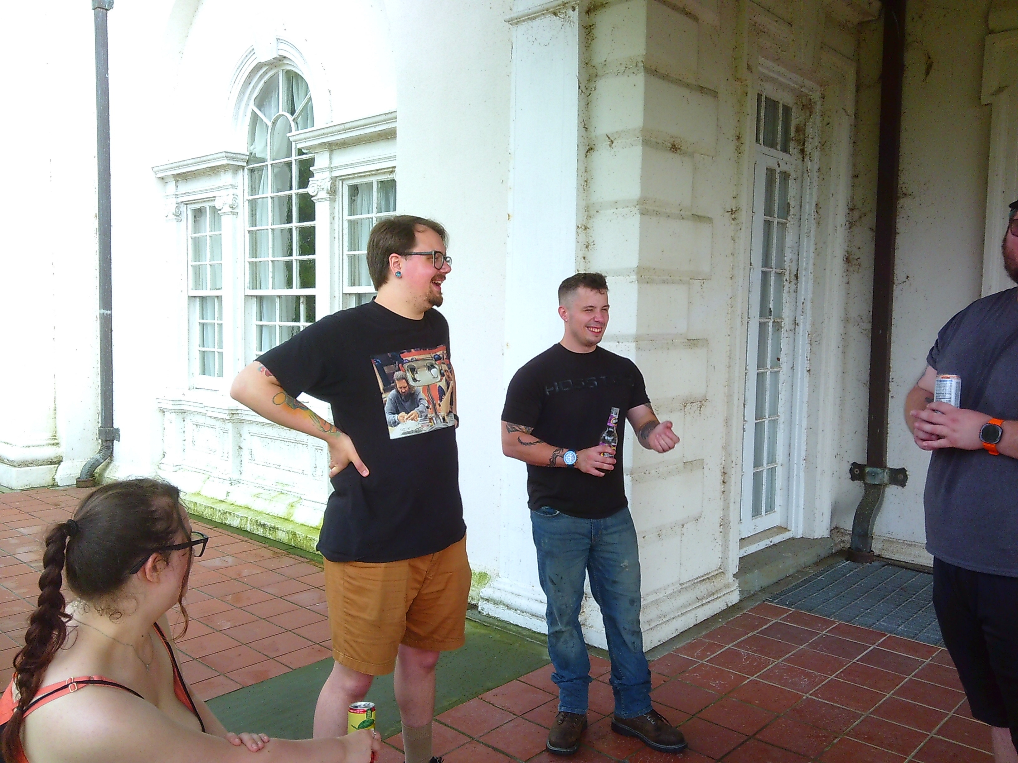 A photo of a woman looking towards two men. One is laughing, the other seems to be in the middle of telling a story