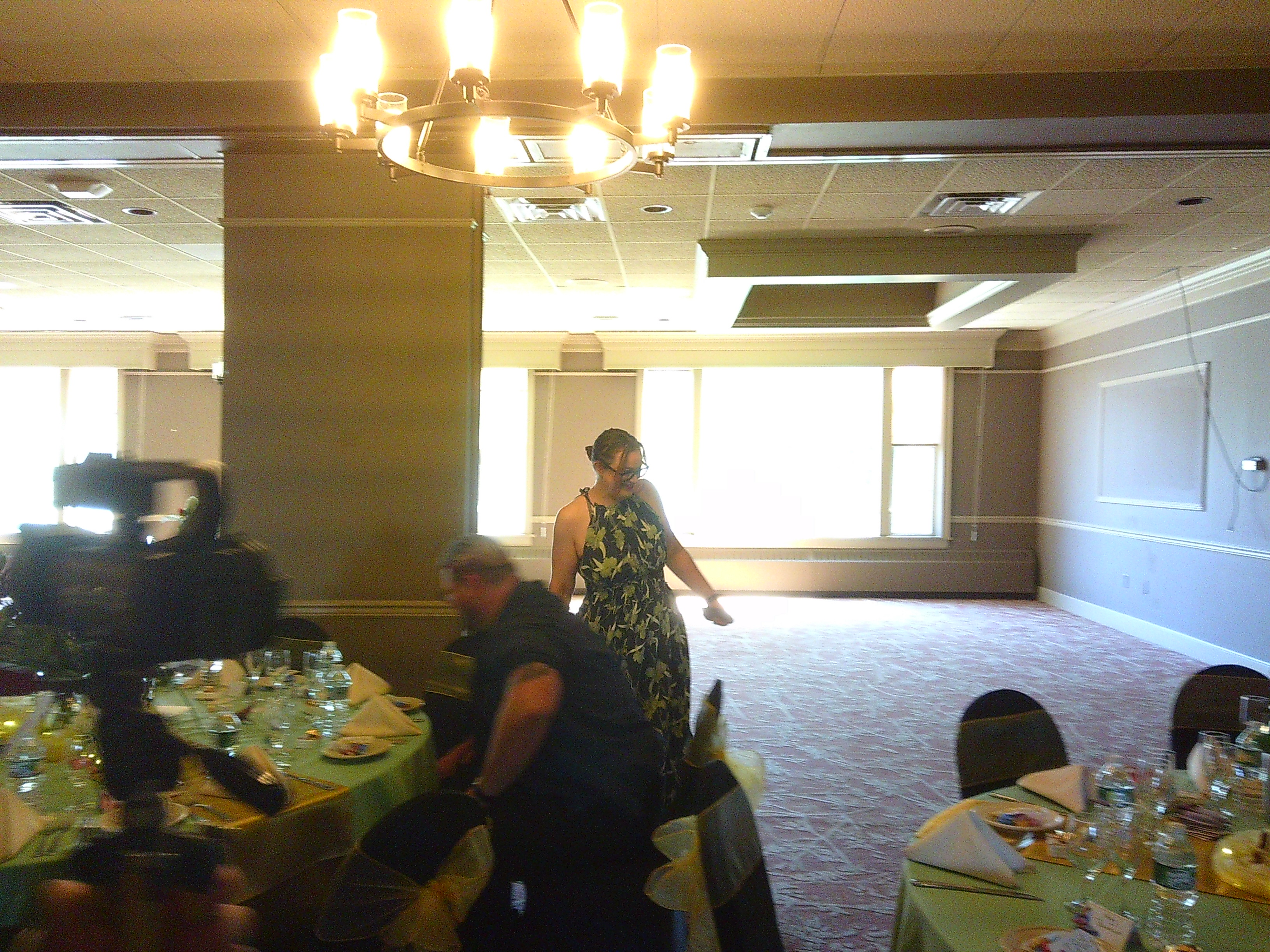 photo of Michelle inside with a lot of tables set up for the wedding. She's standing and has a green flowy dress on