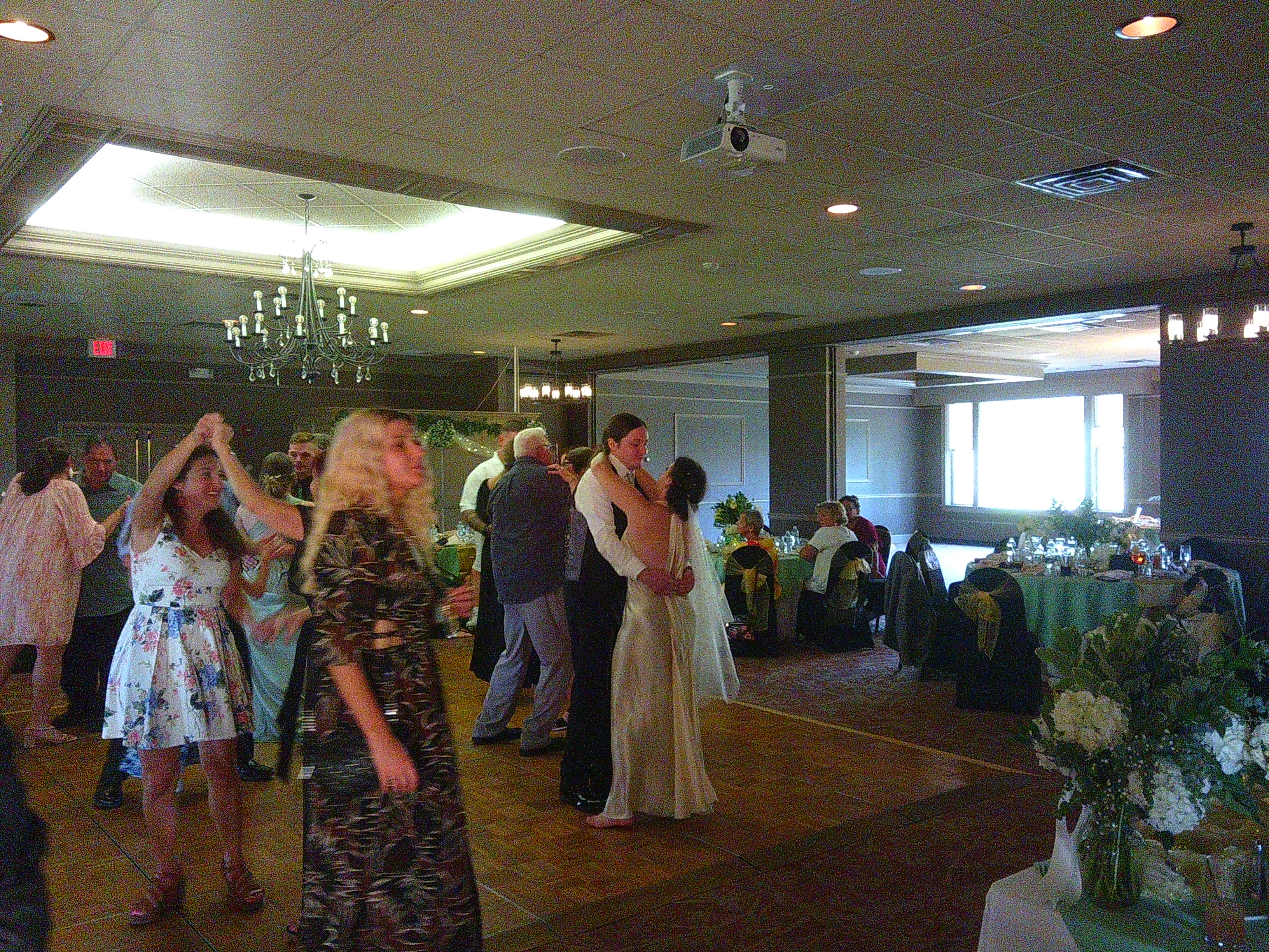 photo of a lot of people dancing on the dance floor, but primarily the bride and groom, Zakiah and Sam. Sam has his arms around Zakiah's waist and they're staring into each others eyes