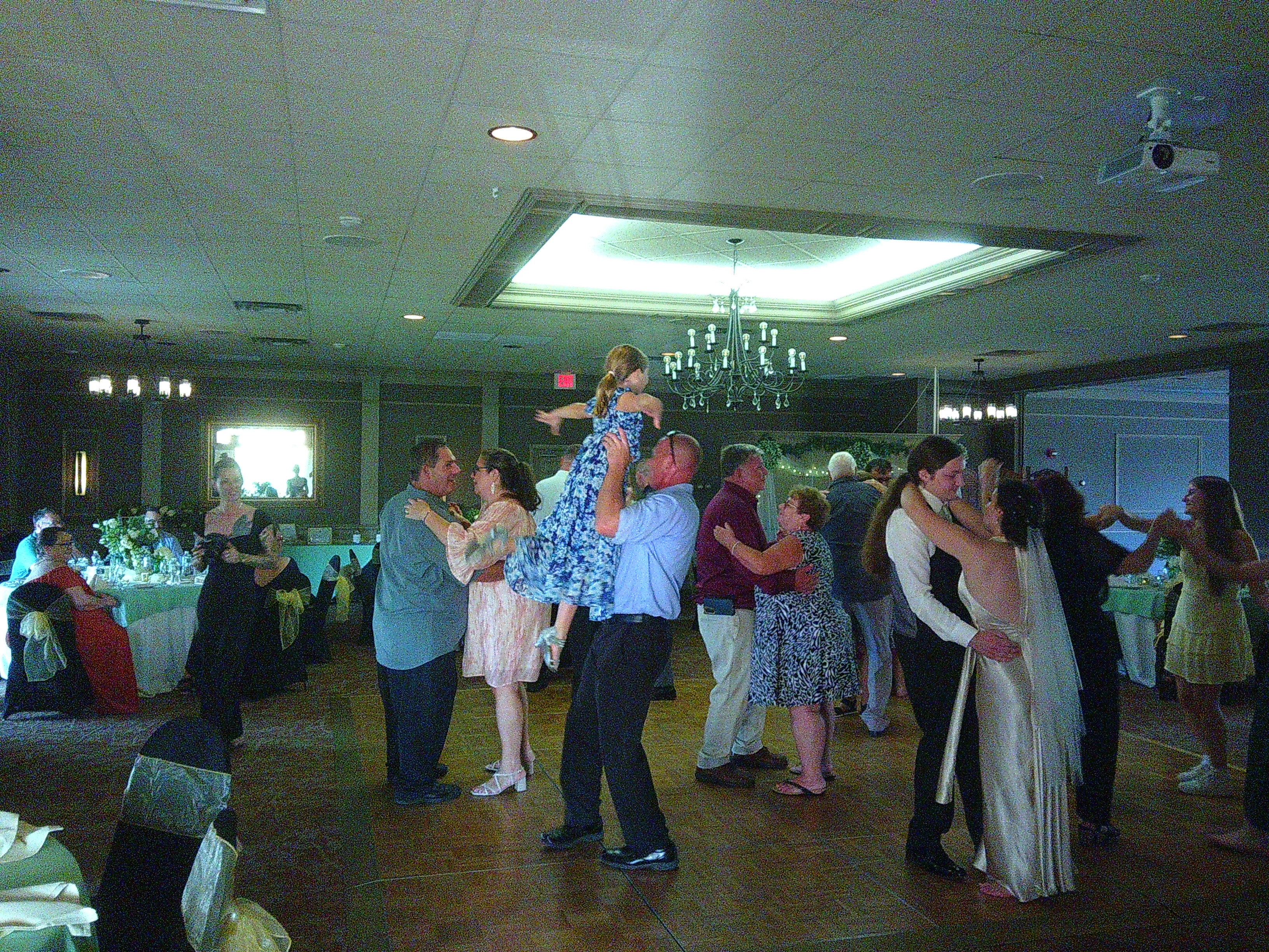 photo of a lot of people on the dance floor. Notably Sam and Zakiah, but also the dad and the daughter from earlier, this time the dad is lifting the daughter up with his hands around her waist.