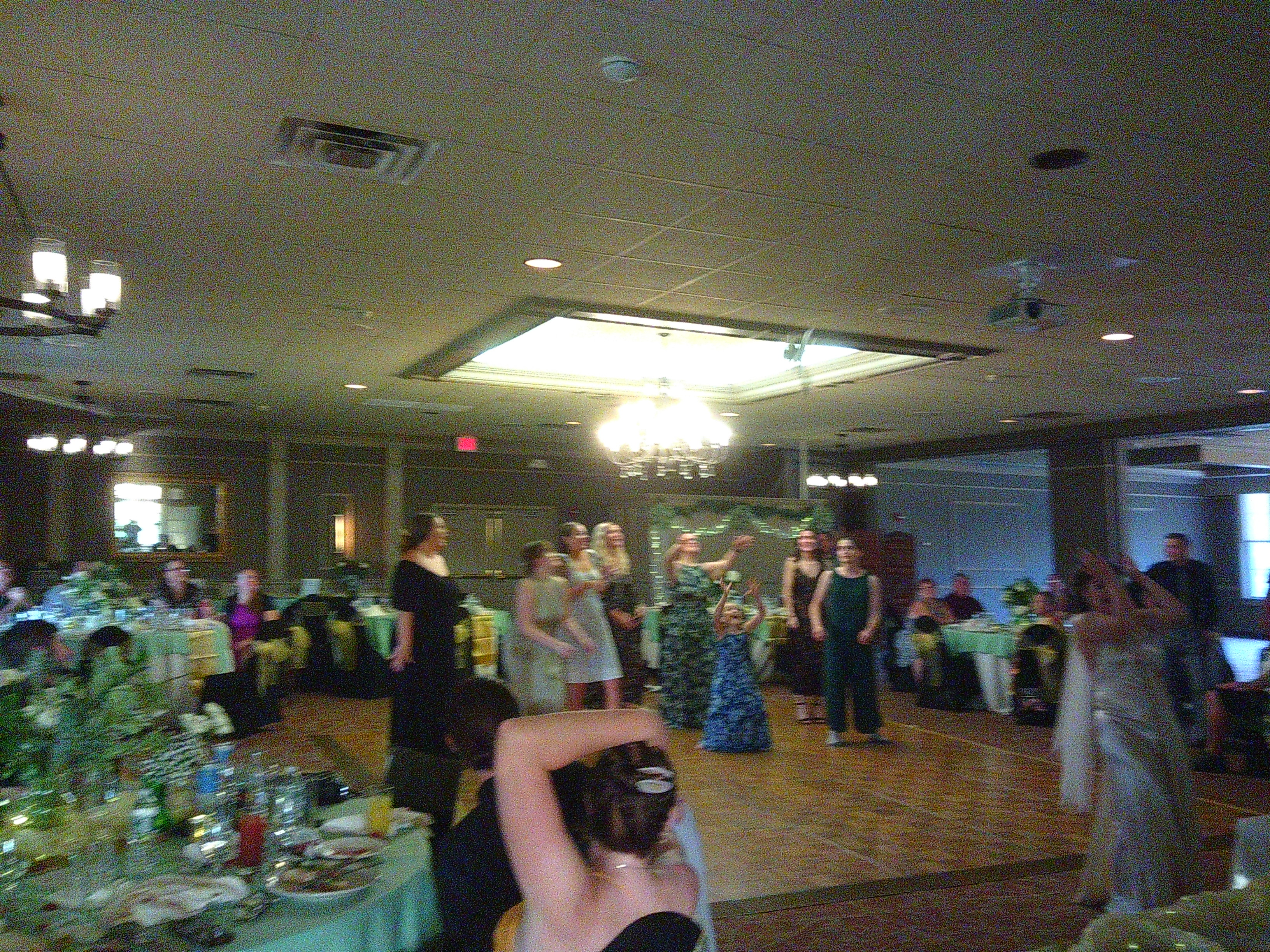 A blurry photo of the bouquet  of flowers mid air as Zakiah (the Bride) throws them behind her. You can see a bunch of women reaching for the flowers