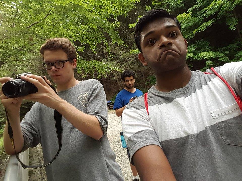 photo of 3 people, one making an exagerrated frowning face towards teh camera, another pointing a DSLR camera off to the distance, and a third a little ways back staring at the camera. Making the frowny face is Fez, the one pointing the DSLR is Chuck, and I'm in the blue