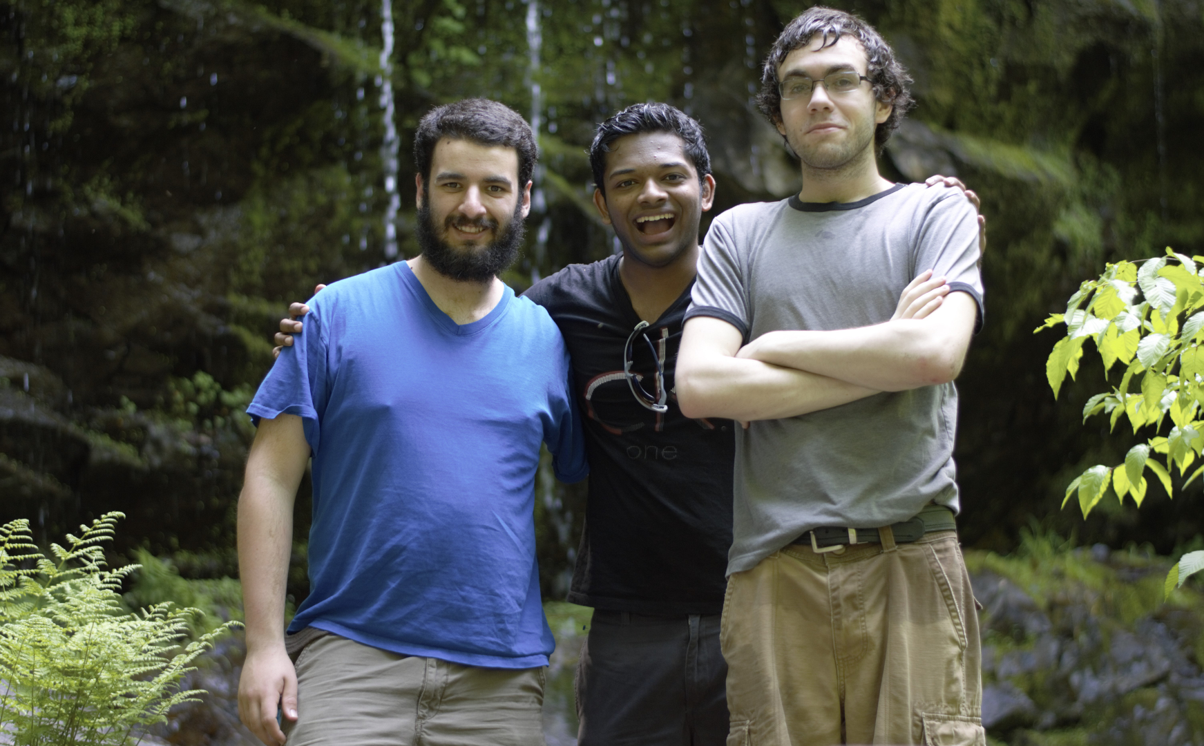 photo of 3 people smiling with a forest waterfall behind them