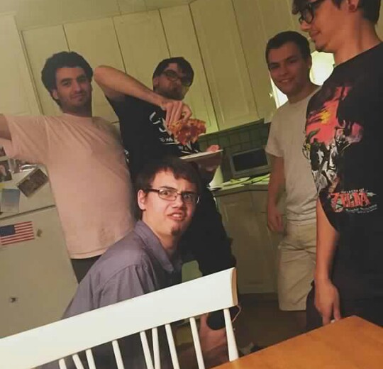 Photo of 5 people making silly faces and expressions in a kitchen. The one in the pink is me, the one with the pizza is Tanner, the one in the white is JC, the one in the black on the right hand side of the image is Aiden, and the one sort of squatting down is Dylan