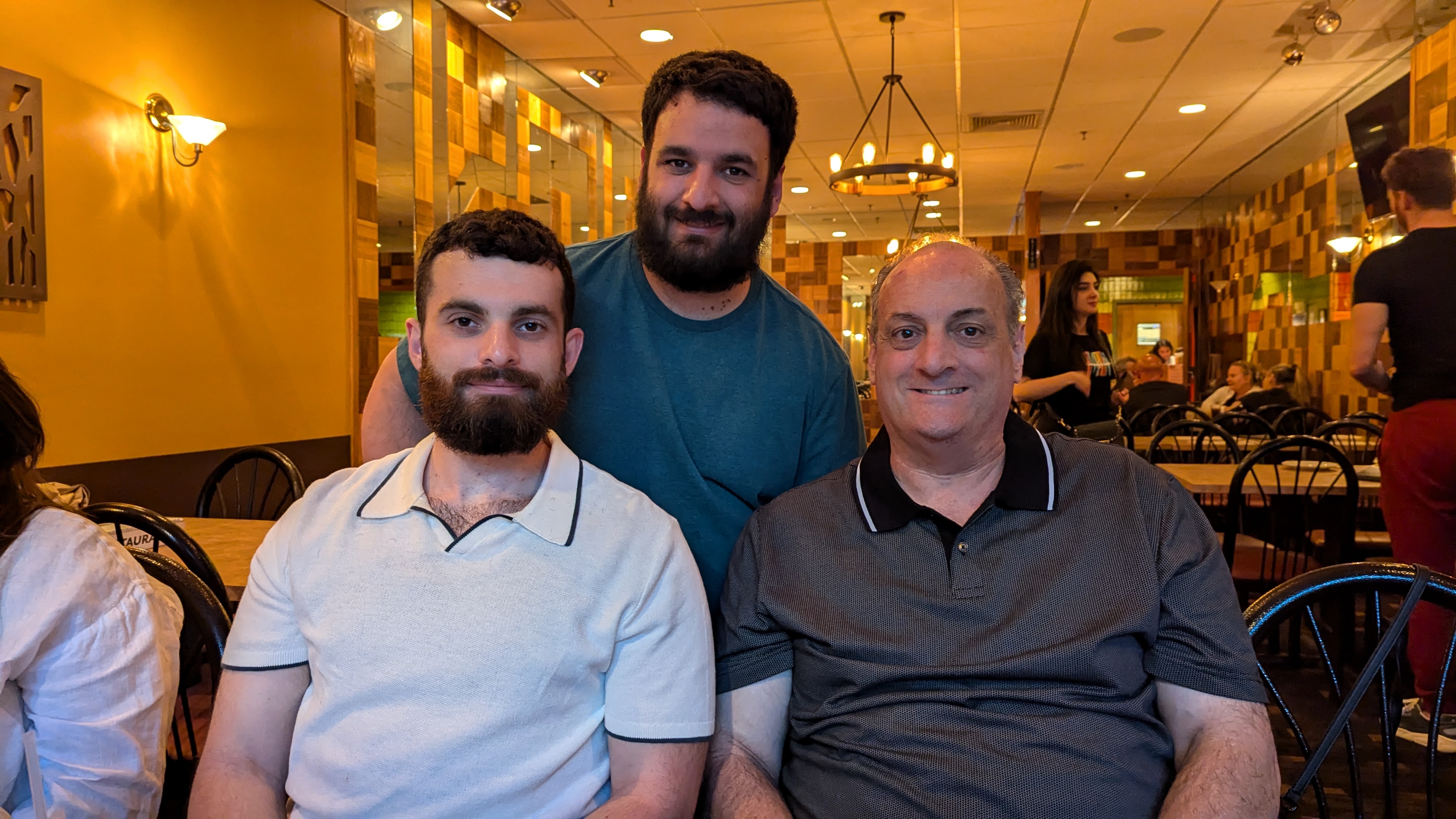 Photo of man and his two sons in a restaurant in nice clothing, all smiling for the camera