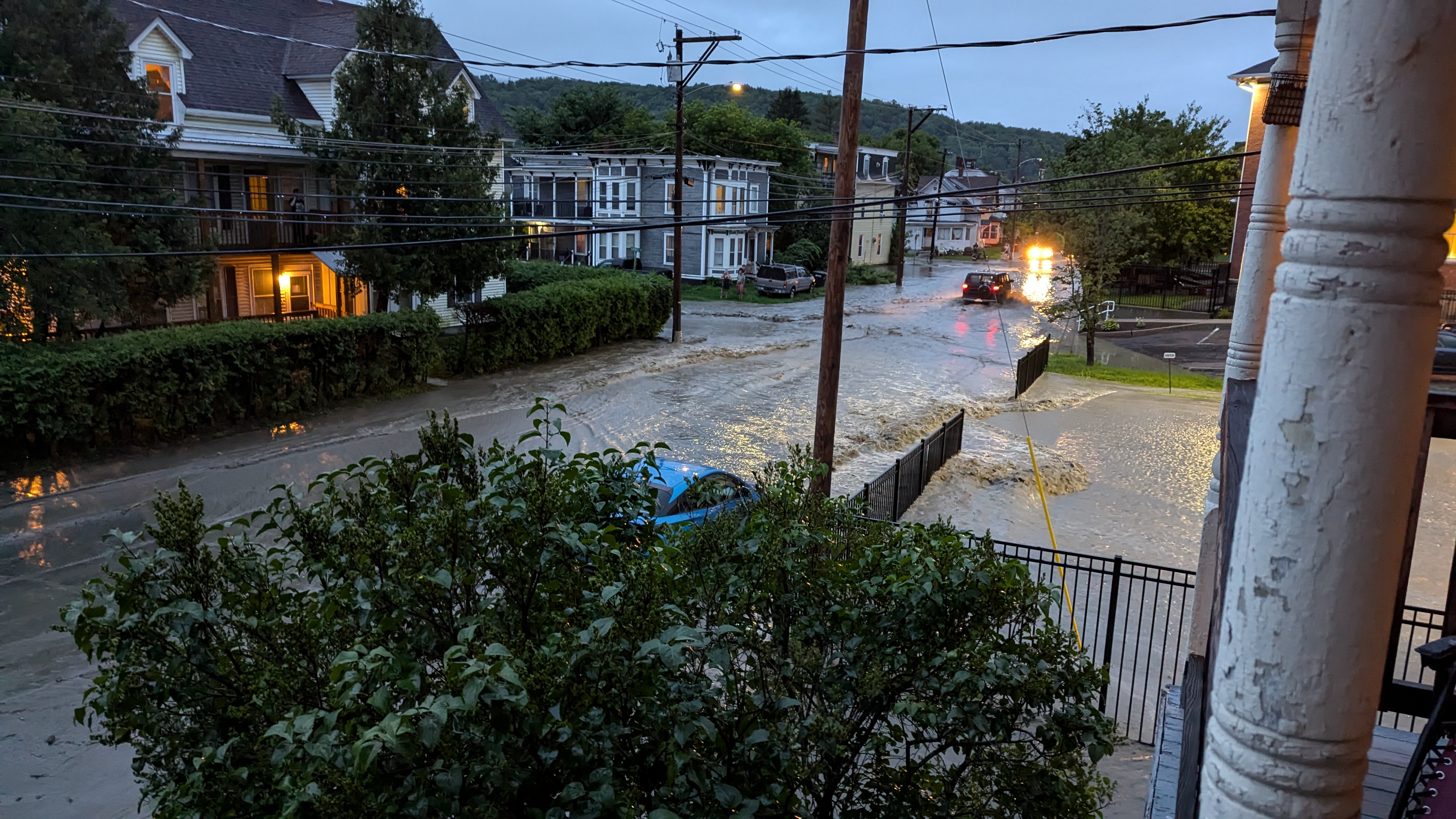 image of a flooded street in a city. You can seem some cars trying to get through the water