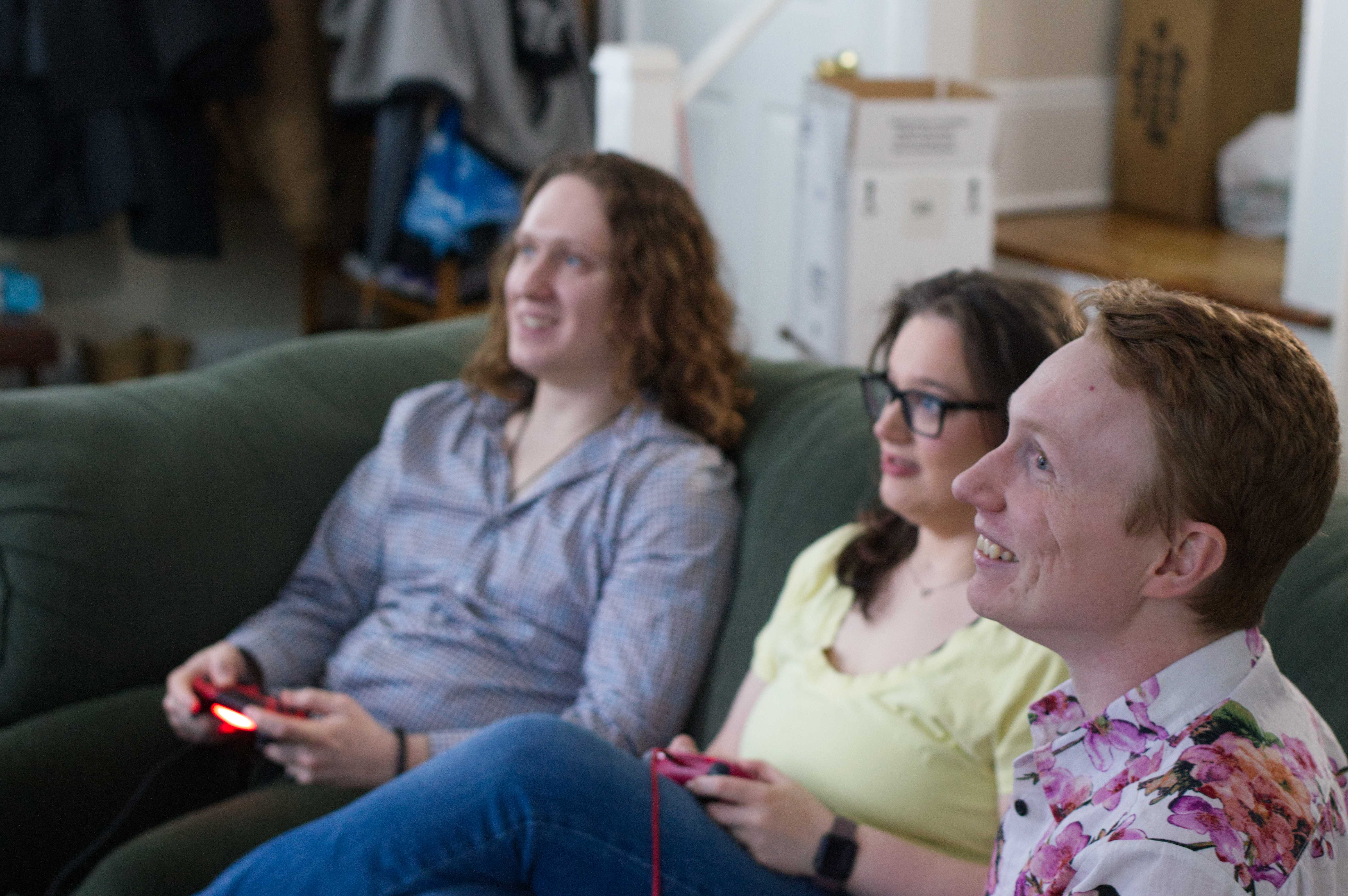 Another photo of Josh, Michelle, and Mat on a couch playing Rivals of Aether. You can see Mat's face better, and both him and Josh look happy