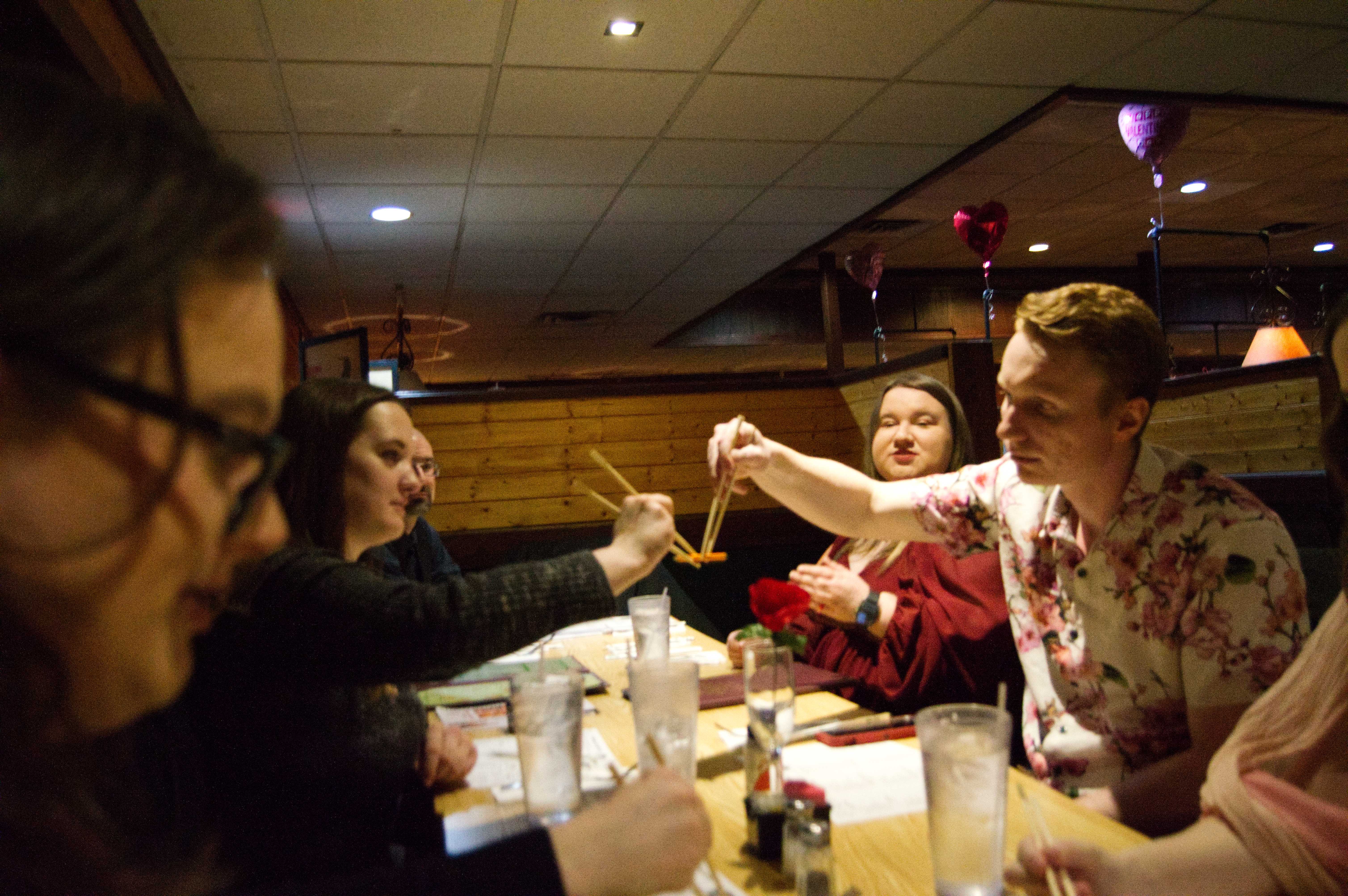 A photo of Mat and Bren using chopsticks to hold up a pencil