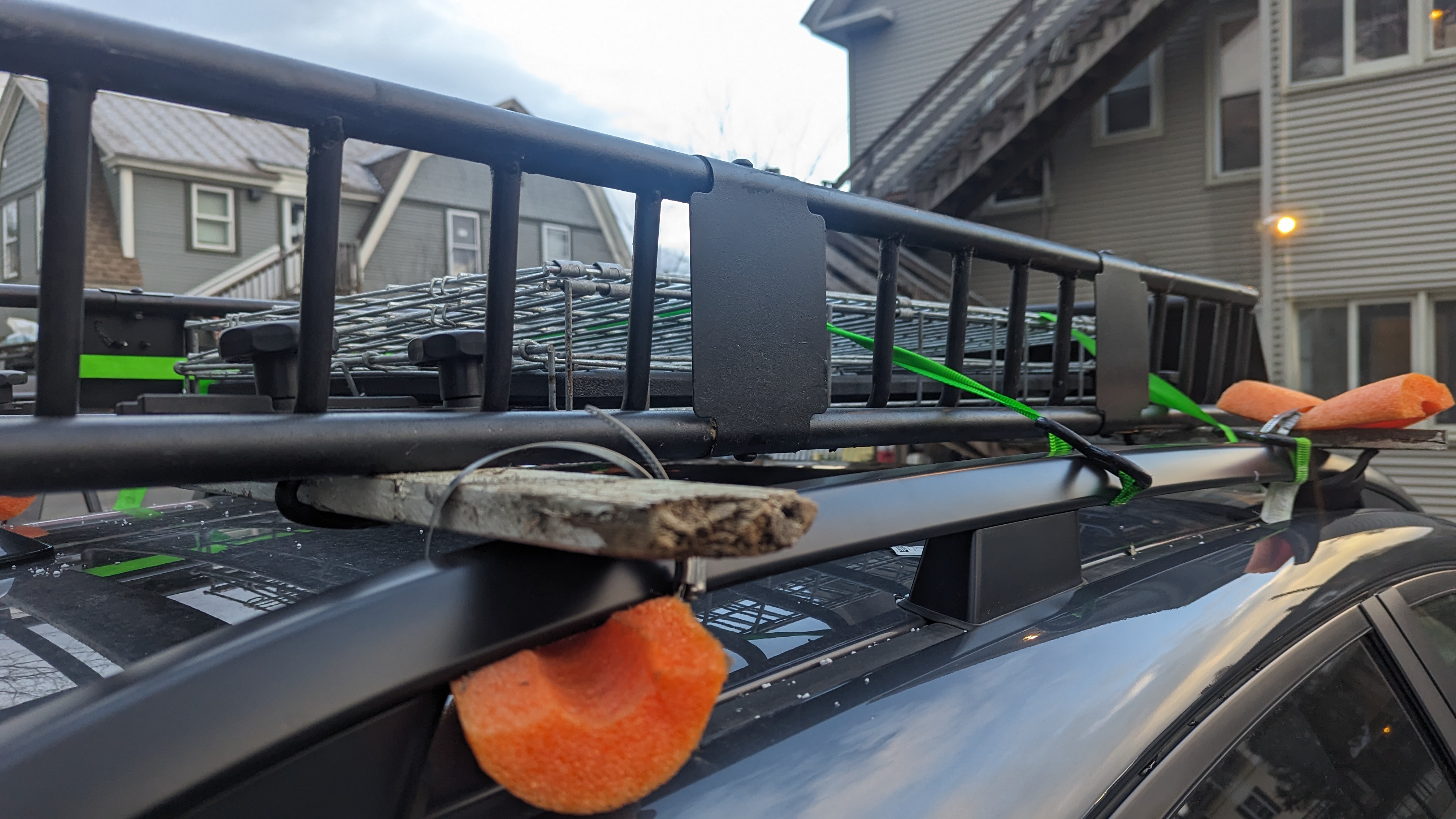 picture of another angle of the roof rack from the previous photo. The wooded crossbars are more well seen as well as the ratchet straps, and a metal cage now being held within the basket on top.