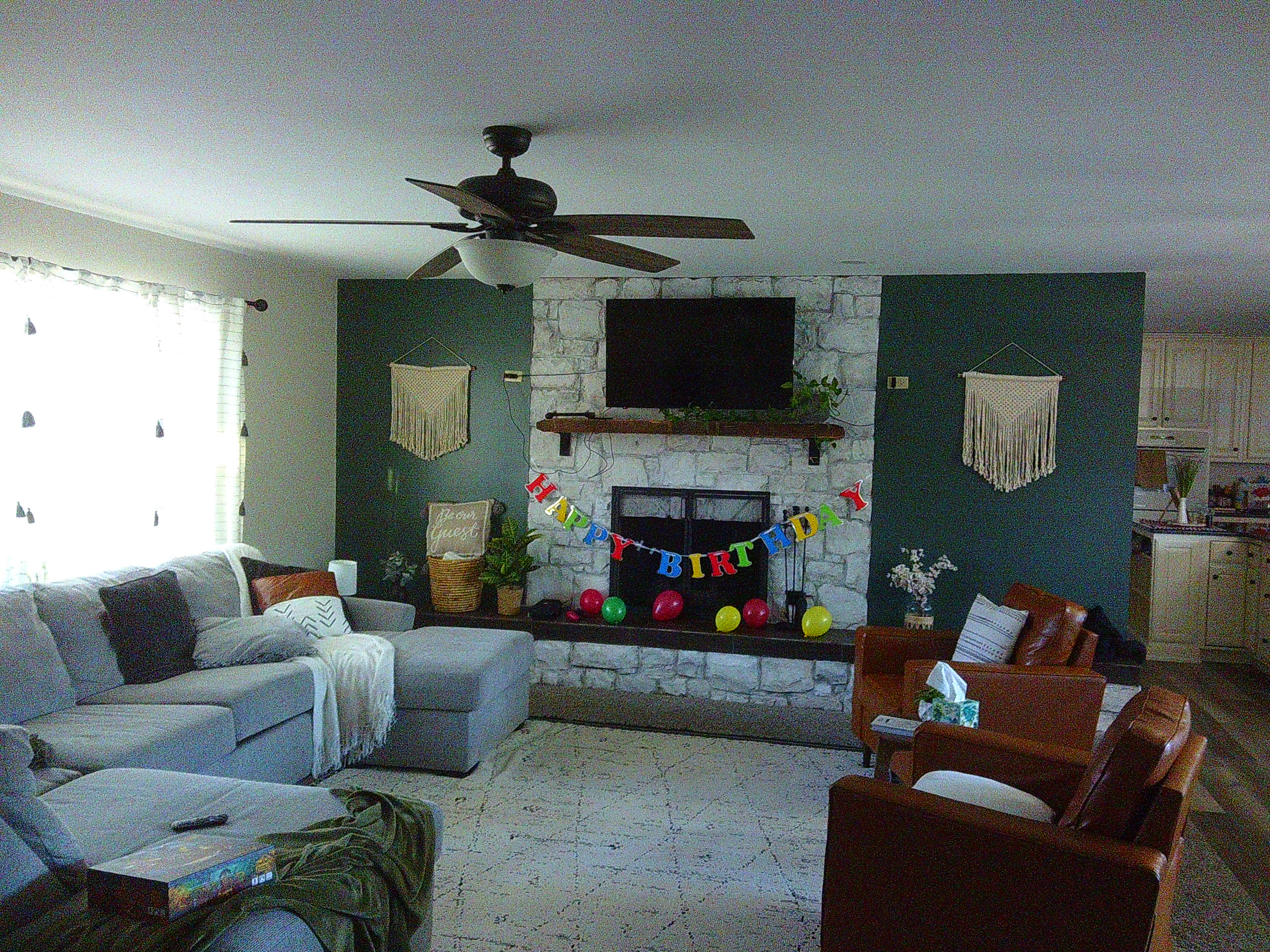 photo of a living room with a fireplace in the center of the frame. There are letters spelling out Happy Birthday over the fireplace, with a bunch of balloons blown up and placed about