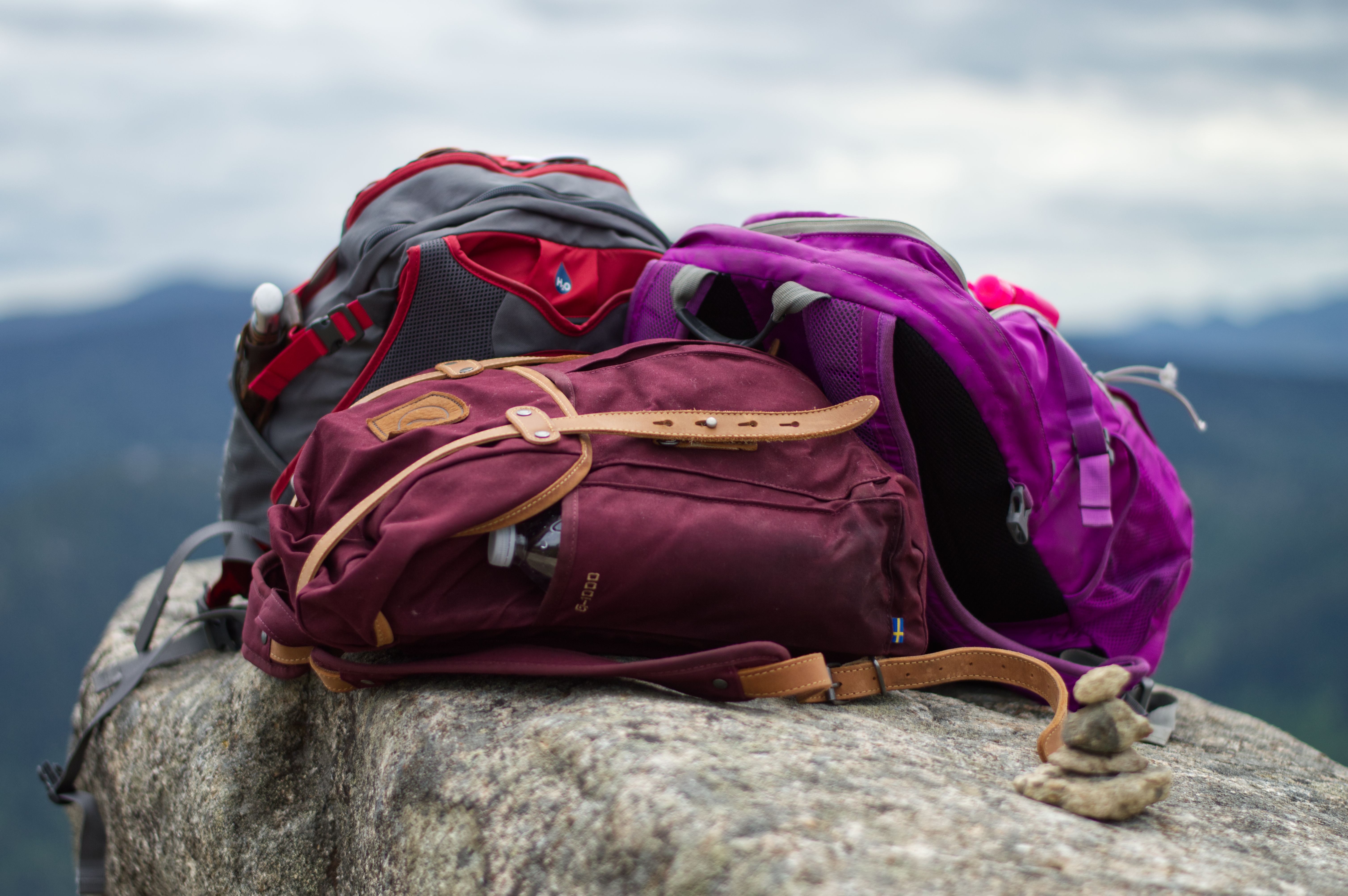 3 hiking backpacks on top of a rock