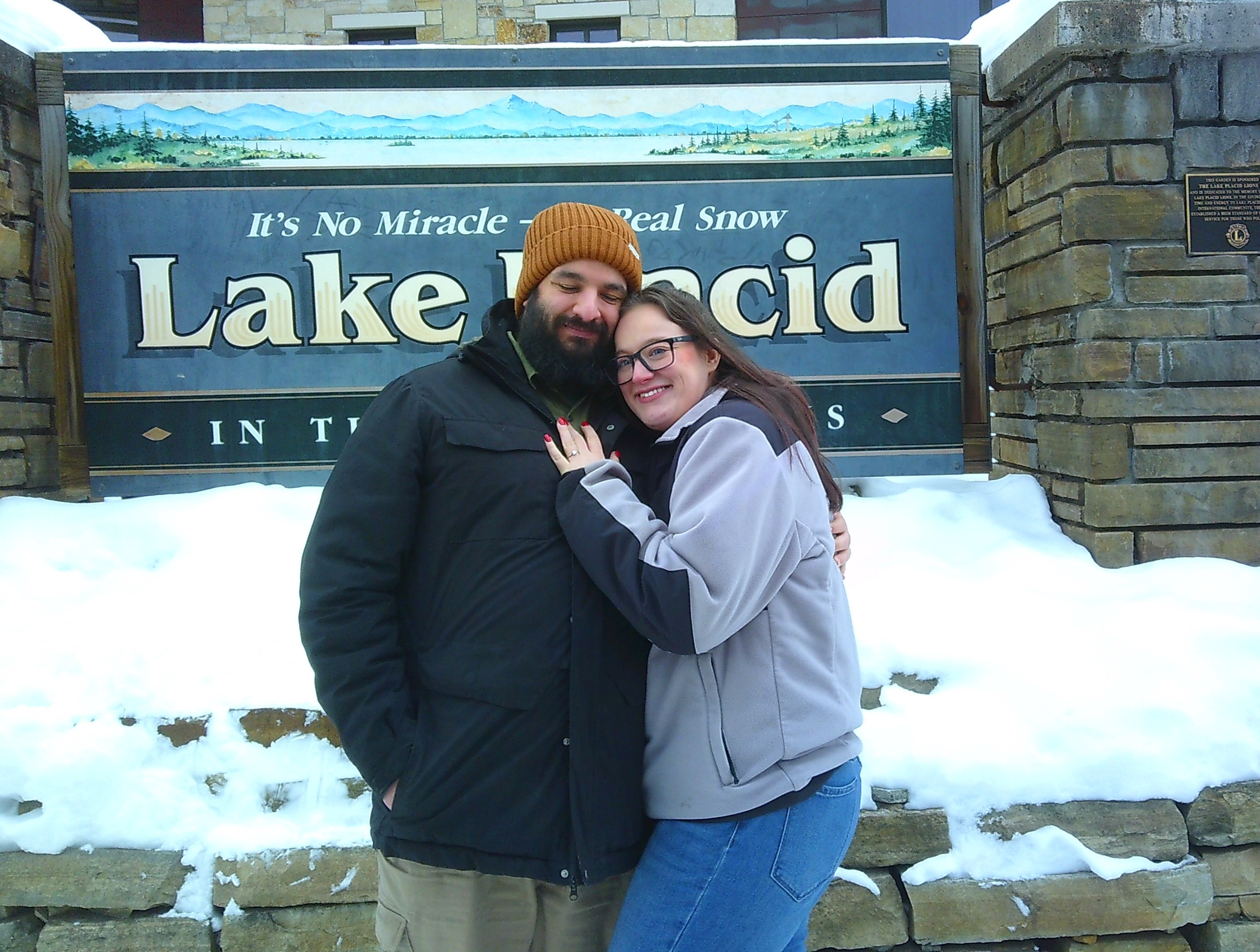 image of Michelle and I hugging in front of a sign that says 'It's no Miracle - it's real snow Lake Placid'