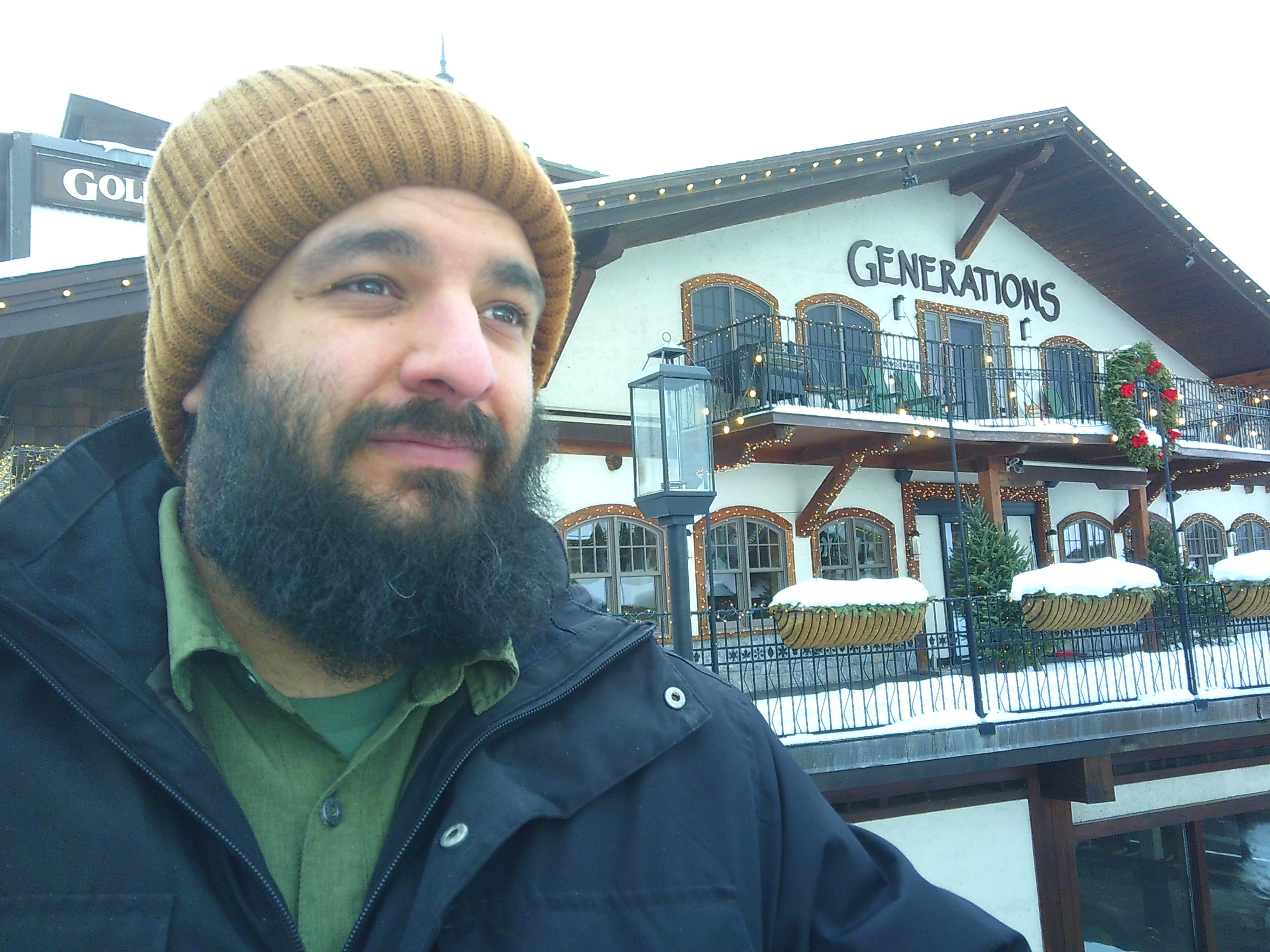 headshot of me in front of a restaurant that says Generations on the side. I'm wearing a brown beanie, and have a full beard