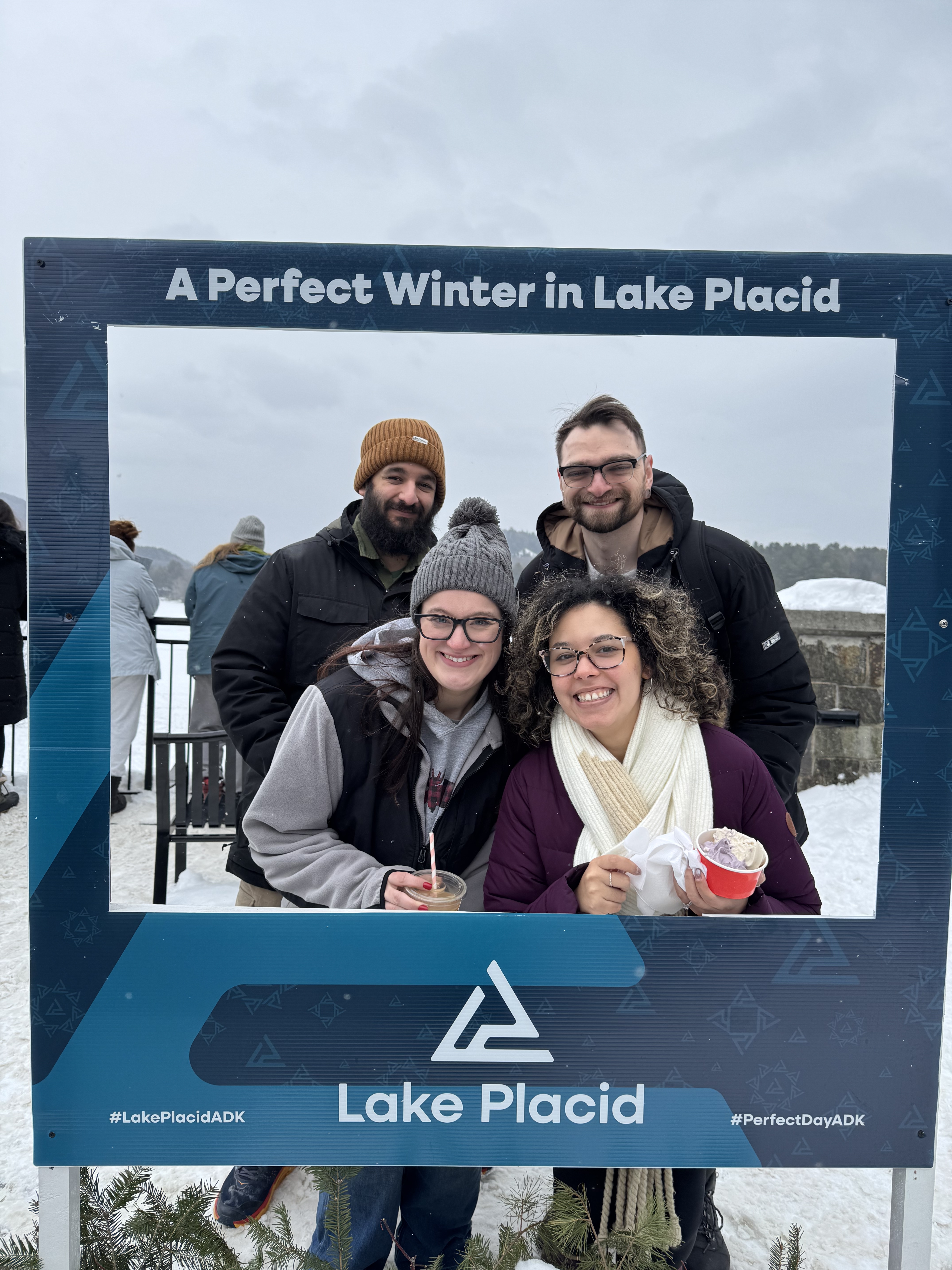 Photo of Tanner, Myself, Michelle, and Ali standing in a frame that says 'A Perfect Winter in Lake Placid'