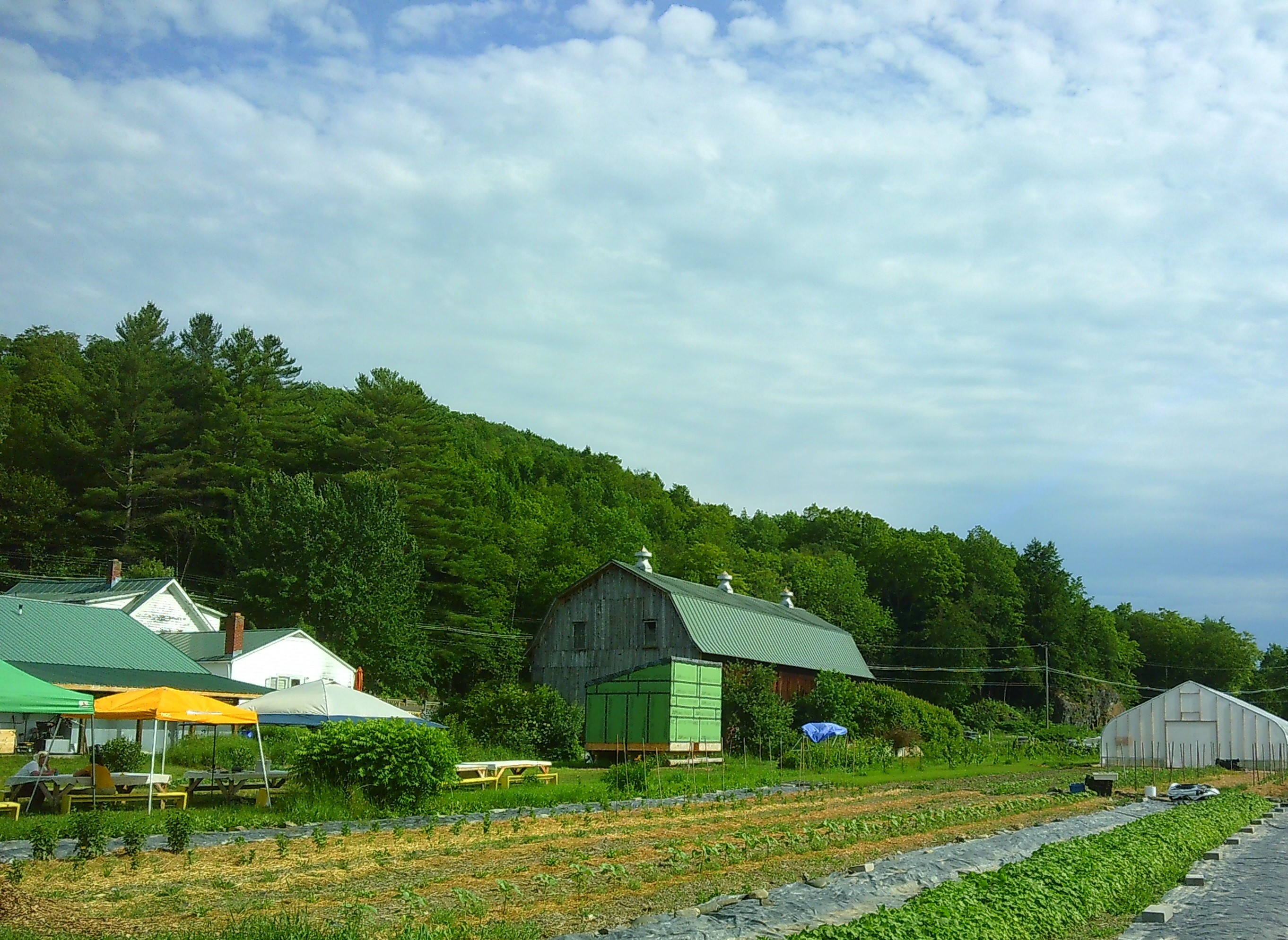 Photo of a barn with green mountain tops behind it, and the sky above it