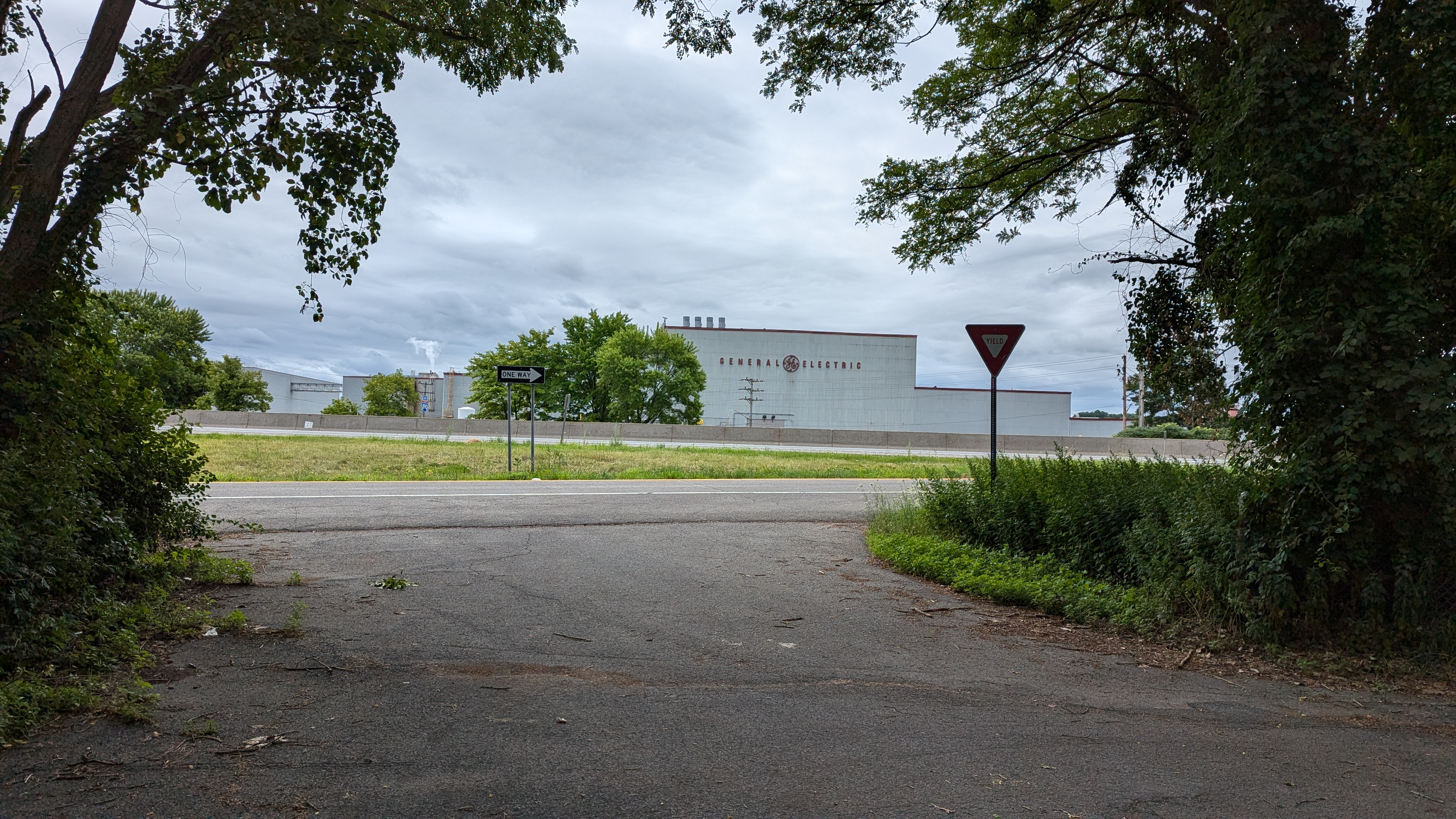 Photo looking at a Genearl Electric plant, which is through some woods and across a highway from where the photo is taken