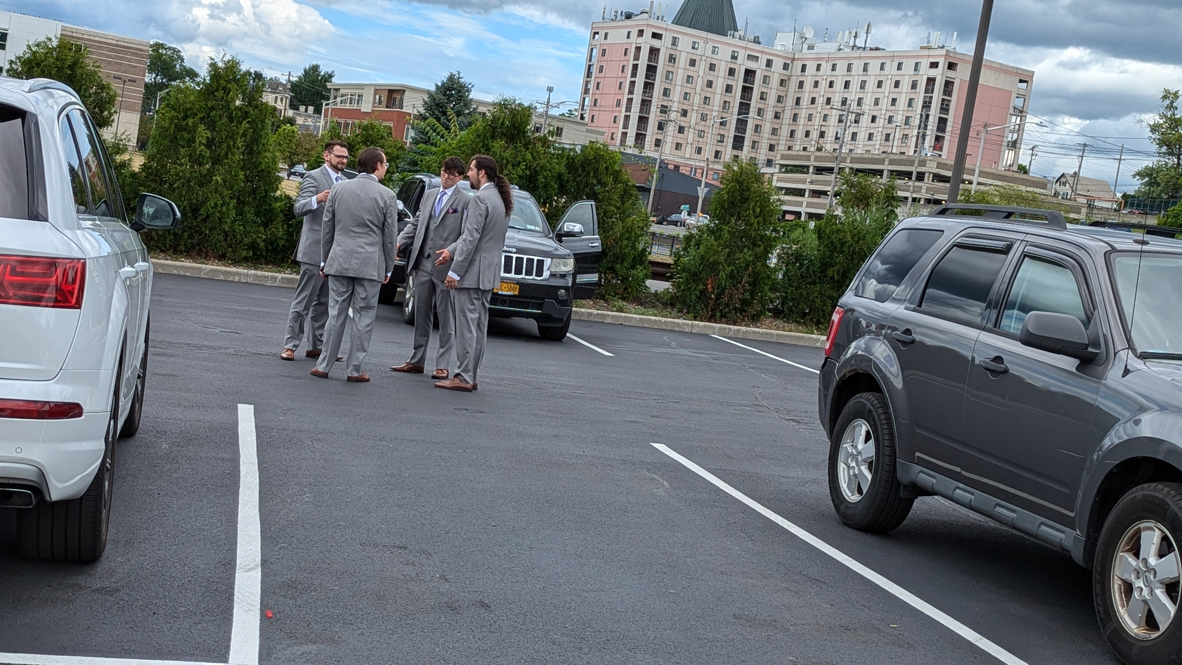 Picture of four men in suits in a parking lot