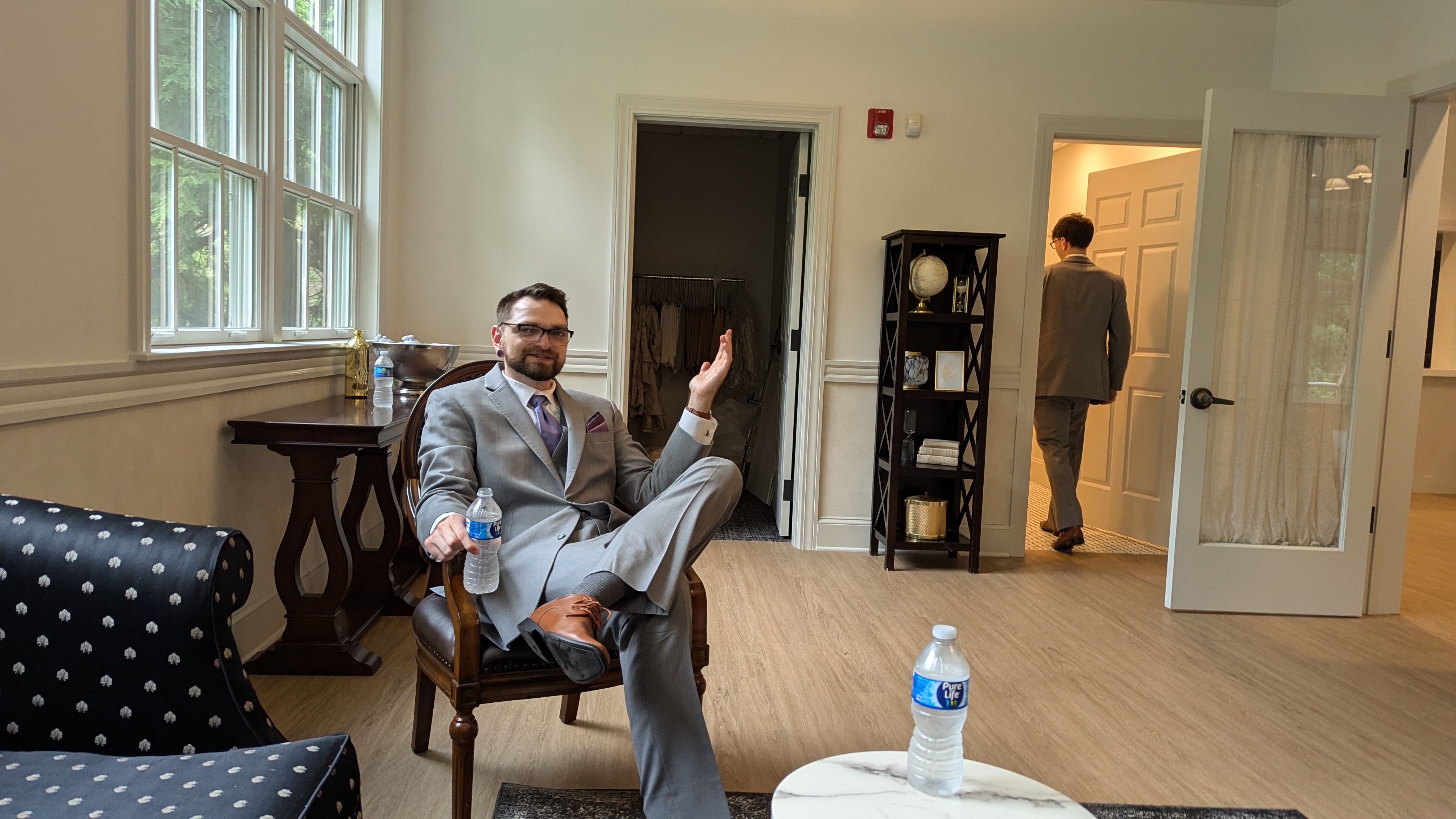 A photo of a man sitting in a chair, legs spread out, who looks to be in the middle of explaining something