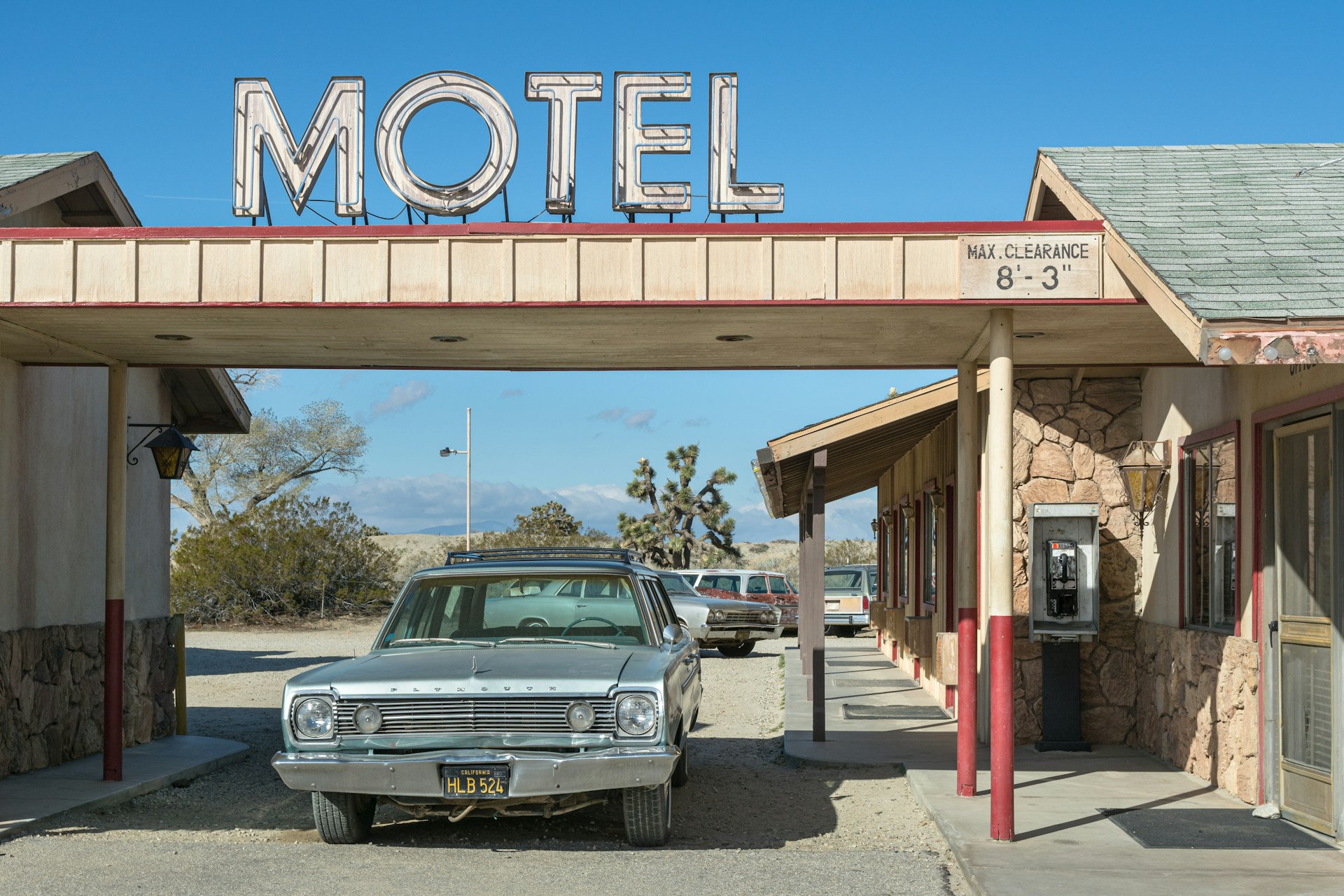 photo of a car sitting under a roof that has the word 'Motel' in big letters above it