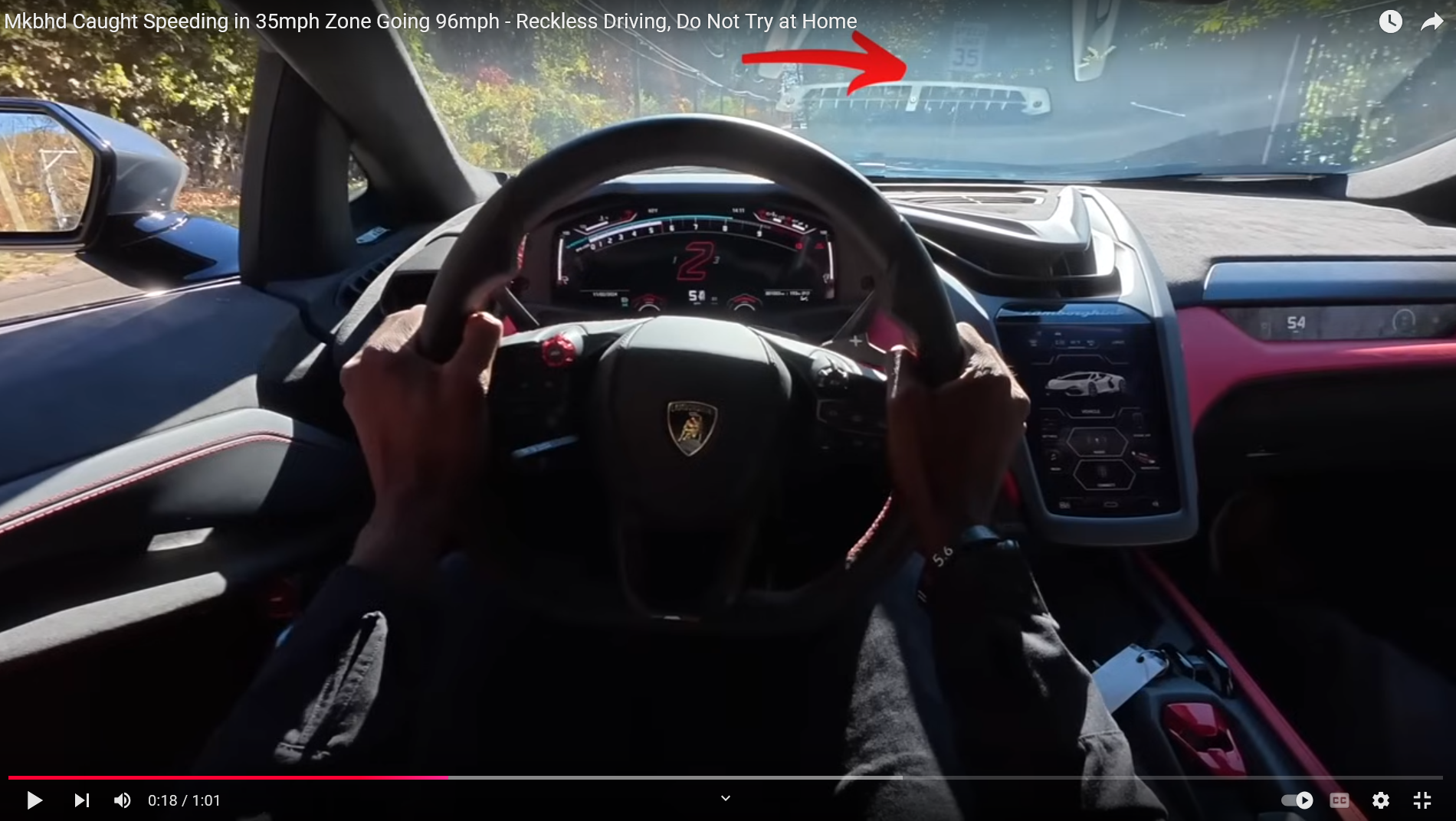 A screenshot from a first person video of MKBHD driving a sports car going 54 mph. You can see past the windshield a sign that says 35mph