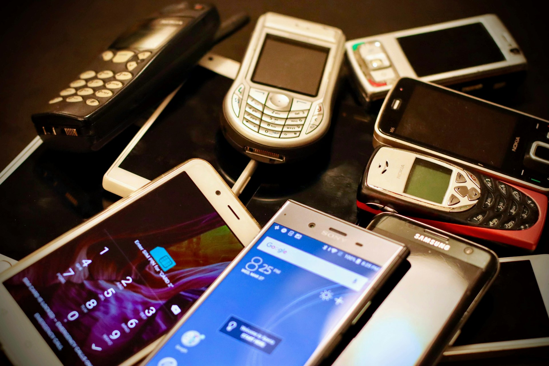 image of a handful of various types of phones on a desk