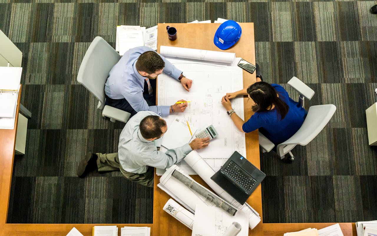 a bunch of people around a table looking at a construction diagram